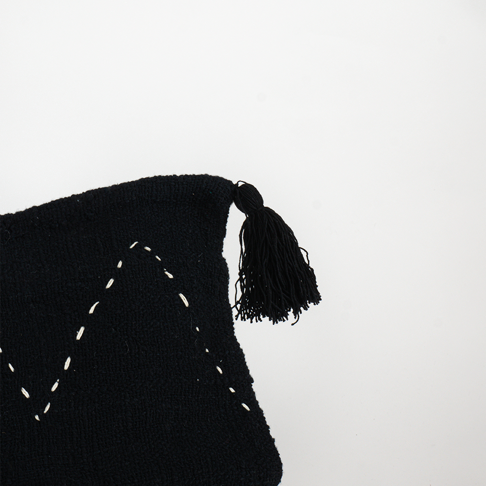 Housse de coussin noire à motifs blanc et pompons noir