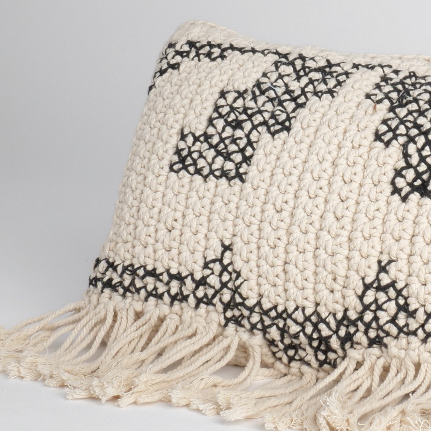 Coussin macramé garni blanc et noir avec franges et motifs géométriques