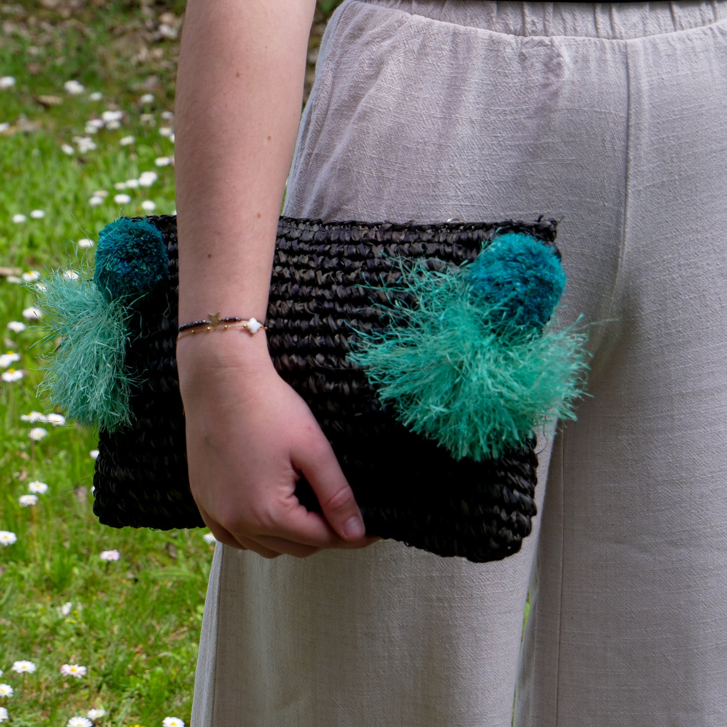 Pochette zippée en raphia noir, pompon bleu